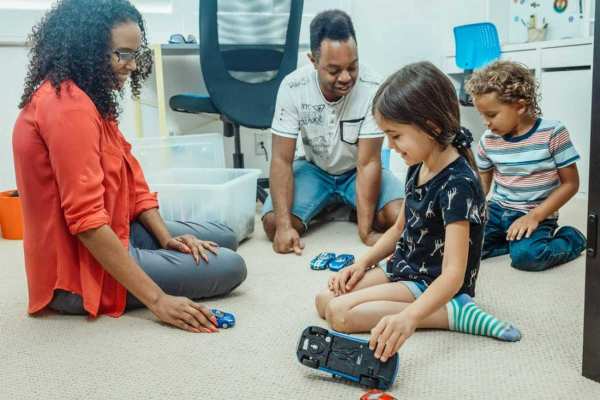 Woman with three kids sitting on the floor playing