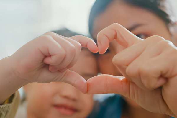 Closeup of young Asian family child making fingers heart shaped signs 