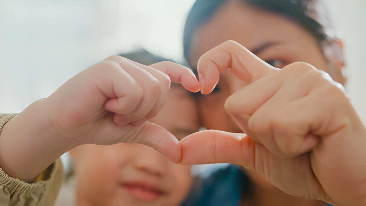 Closeup of young Asian family child making fingers heart shaped signs 